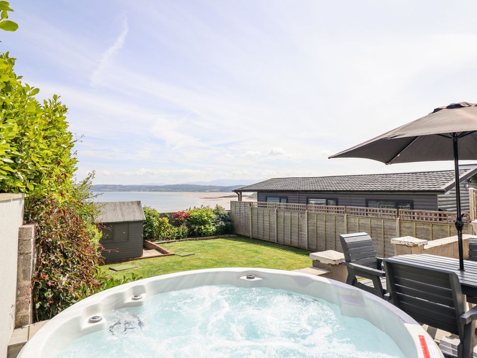 A garden with a hot tub and a view of the sea at Bryn Mor in Benllech