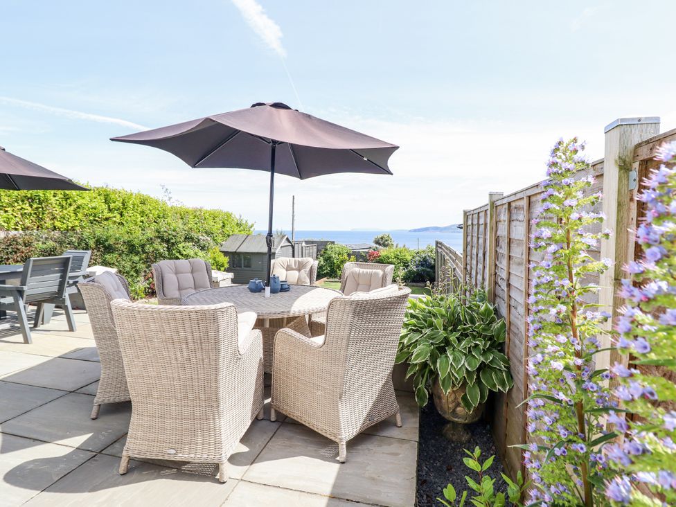A garden with dining table and chairs under an umbrella at Bryn Mor in Benllech