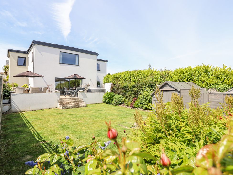 A garden with a house and patio furniture at Bryn Mor Benllech
