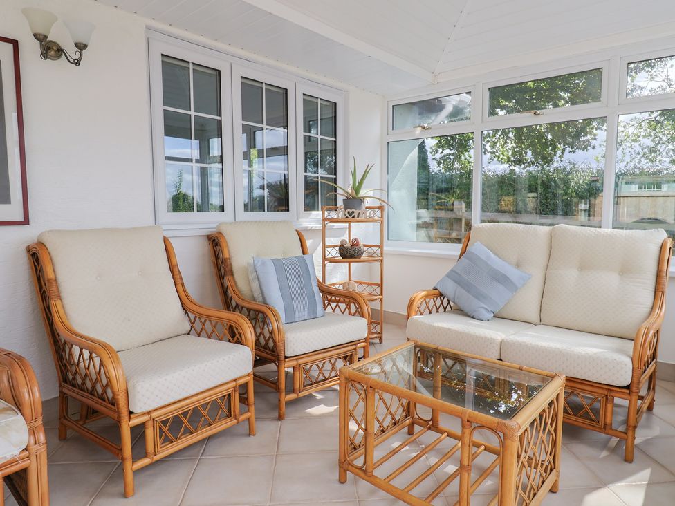 A conservatory with seating and a glass table at Rainbow View Churchstanton near Churchinford