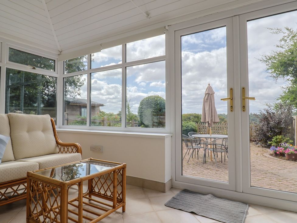 A conservatory with a sofa and table at Rainbow View Churchstanton near Churchinford