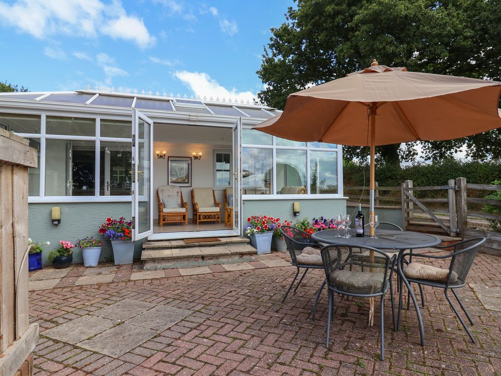 An outdoor patio with a table and chairs at Rainbow View in Churchstanton near Churchinford