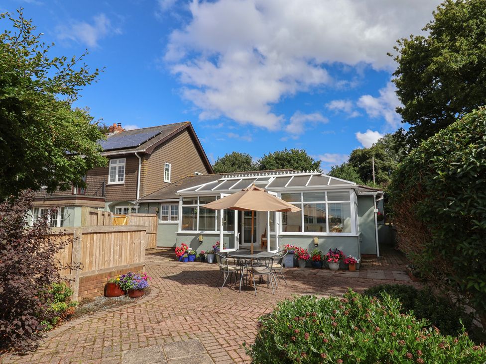 A garden with a conservatory and outdoor seating at Rainbow View Churchstanton near Churchinford