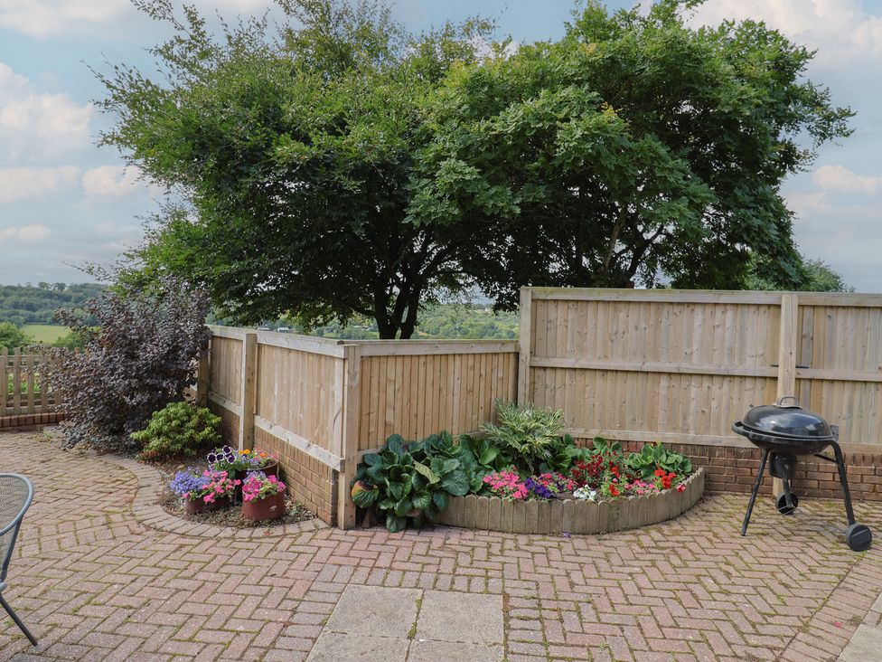 A garden with flowers and a grill at Rainbow View in Churchstanton near Churchinford