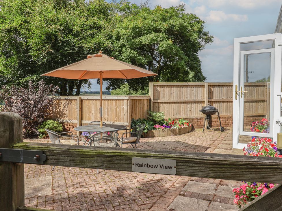 A garden with a seating area and umbrella at Rainbow View Churchstanton near Churchinford