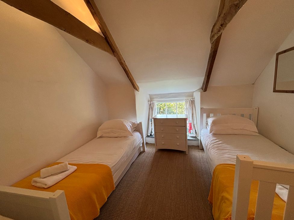 A bedroom with two beds and a dresser at Aaron's Cottage in St Teath