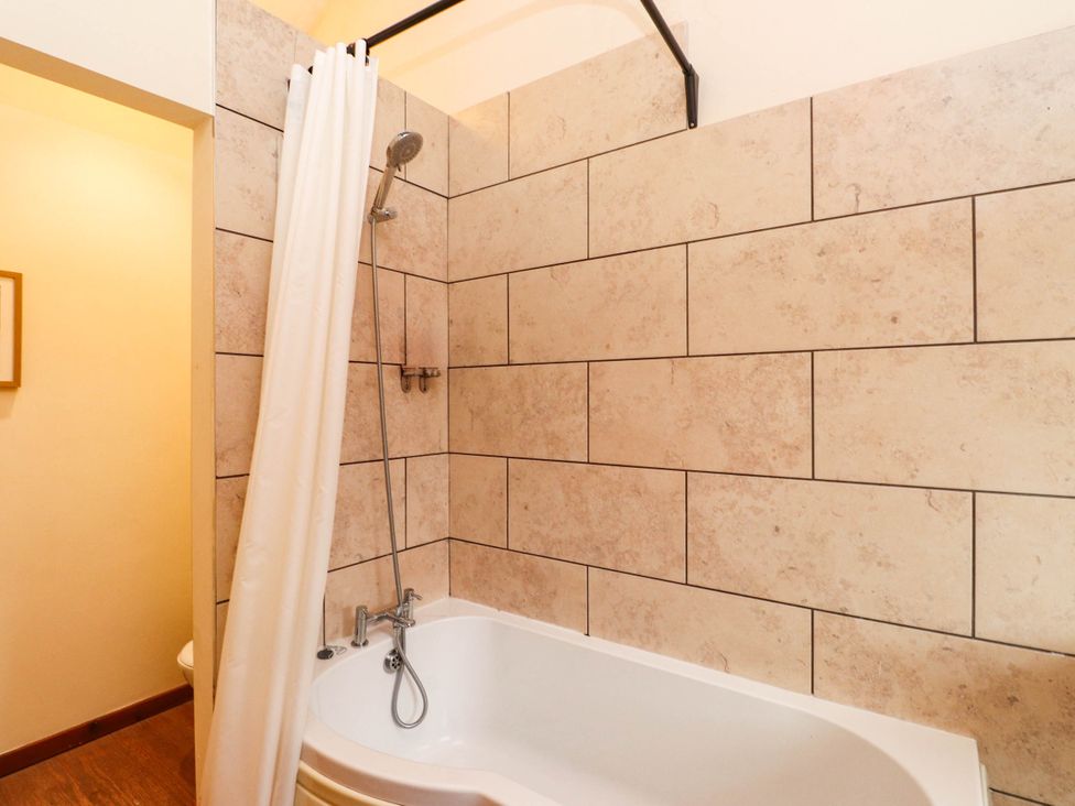 A bathroom with a bathtub and shower in a tiled enclosure at 11- 13 High Street