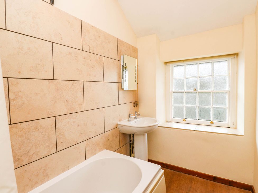 A bathroom with a bathtub, sink, and window at 11- 13 High Street