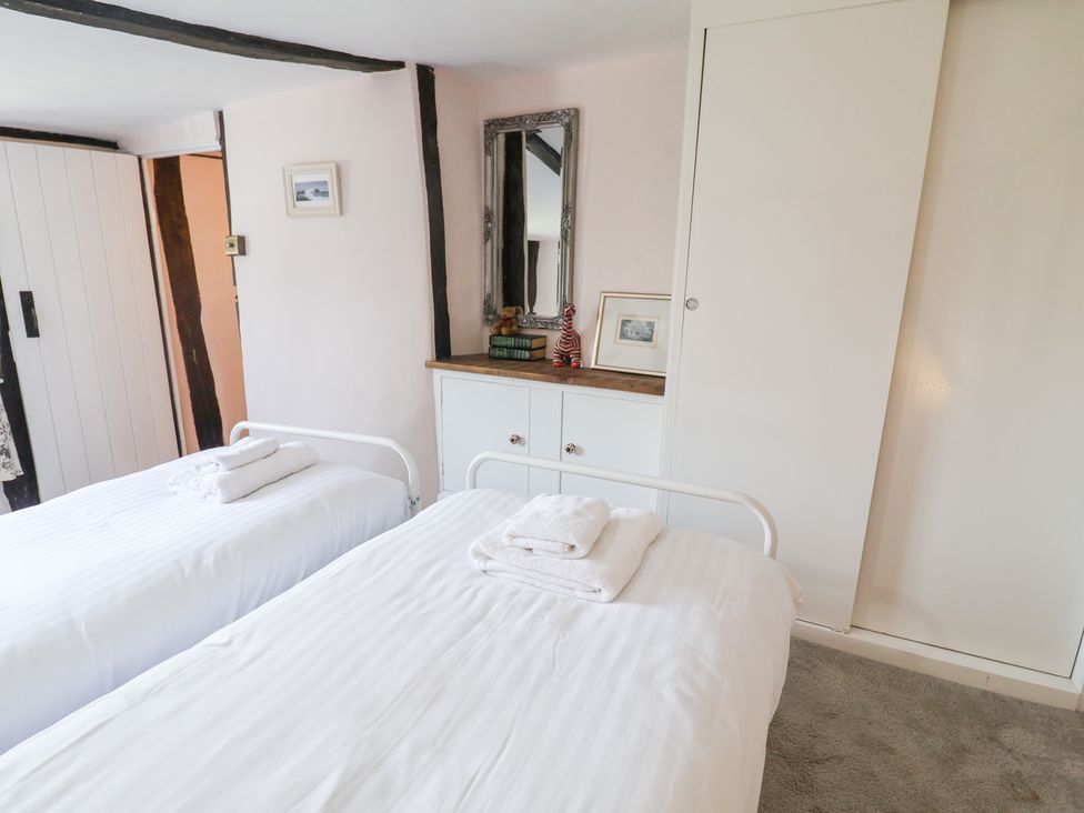 A bedroom with twin beds and a mirror at Rhubarb Cottage Ufford near Woodbridge