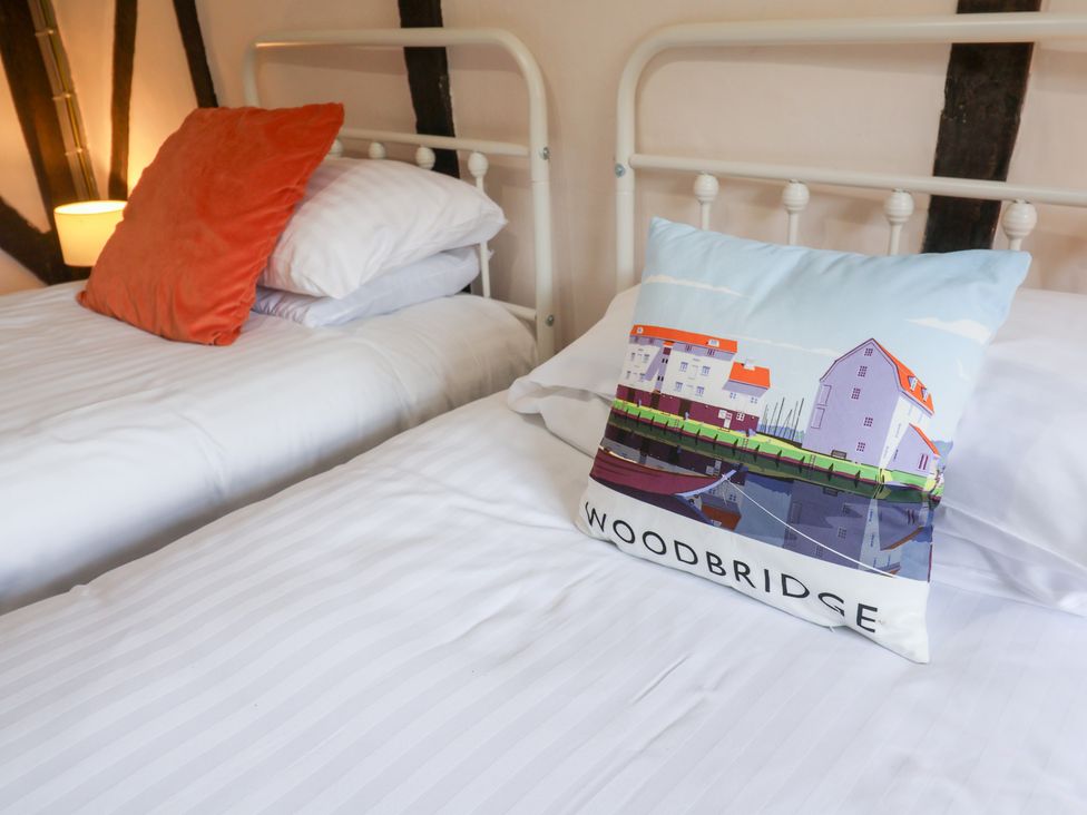 A bedroom with two beds and a decorative pillow at Rhubarb Cottage Ufford near Woodbridge