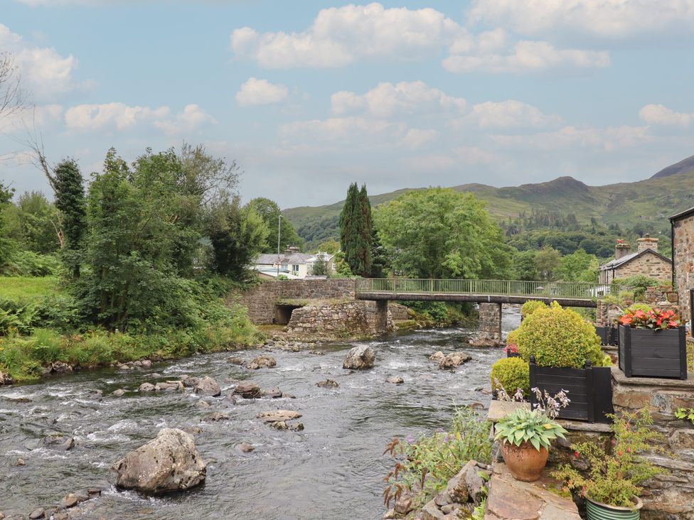 A river with a bridge surrounded by greenery at Riverside Cottage Beddgelert