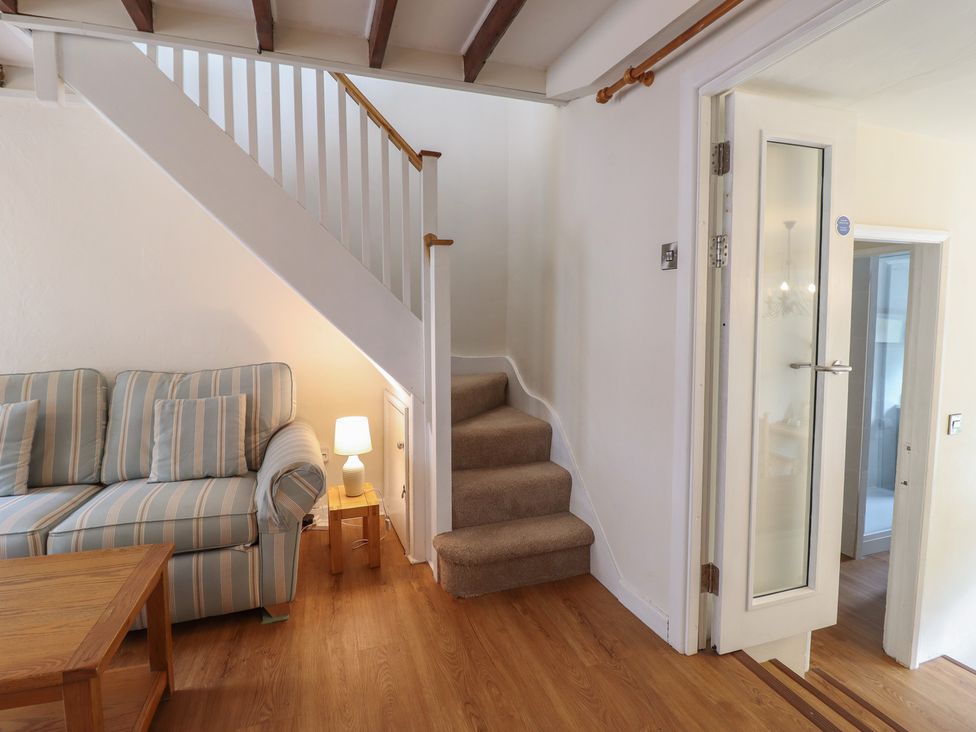 A living room with a sofa and stairs at Riverside Cottage in Beddgelert