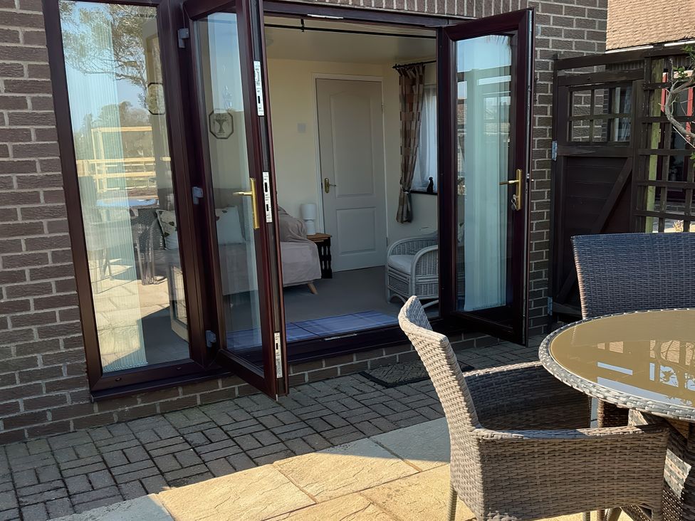 An outdoor area with a table and chairs beside glass doors at Penn Lea in Penally