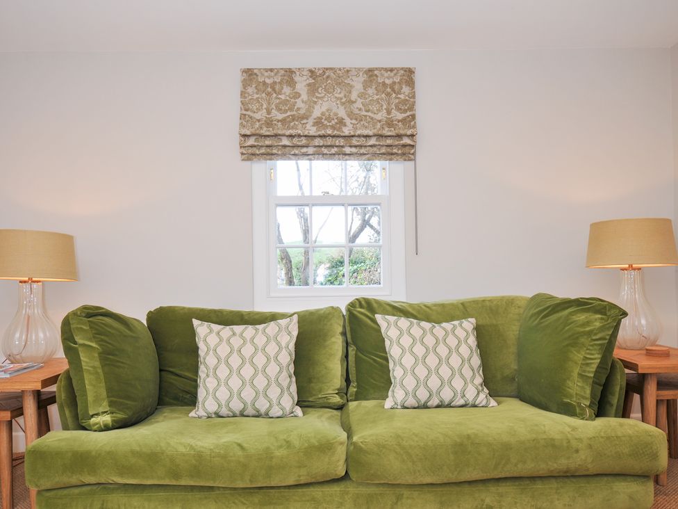 A living room with a green sofa and decorative cushions at Mermaid Cottage in Port Isaac