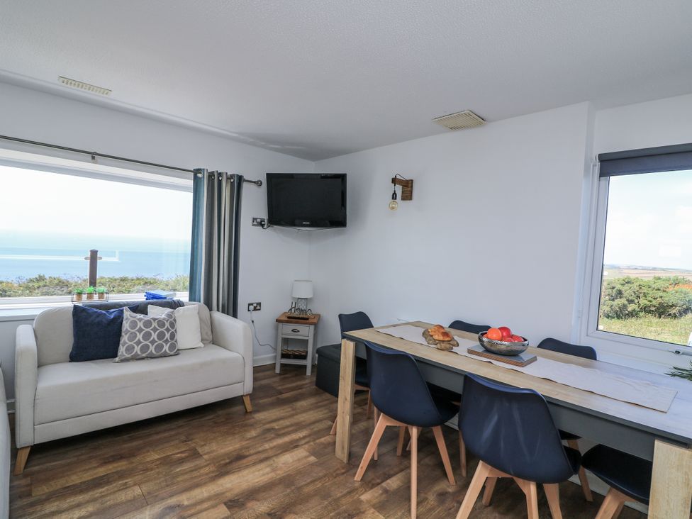 A living room with a sofa and dining table at Sunset Sea View Chalet in Millbrook