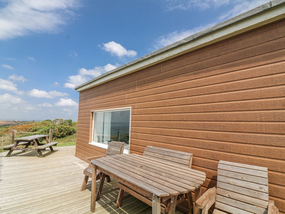 A wooden table and chairs on a deck at Sunset Sea View Chalet in Millbrook