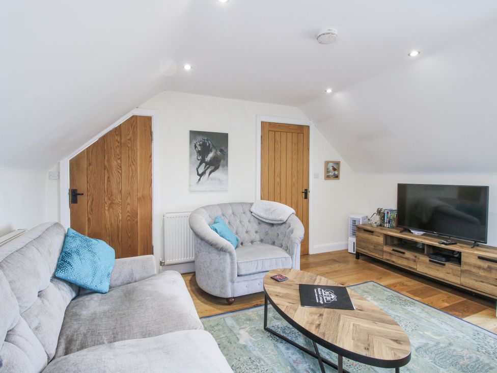 A living room with a sofa, armchair, and television at Stable Cottage in Norbury near Bishop's Castle