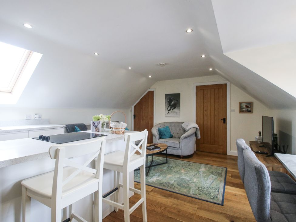 A living room with a kitchen bar and sofa at Stable Cottage in Norbury near Bishop's Castle
