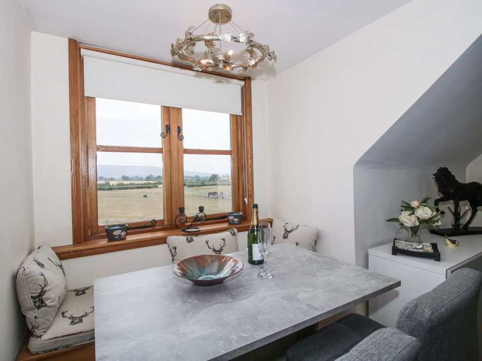 A dining area with a table and window at Stable Cottage Norbury near Bishop's Castle