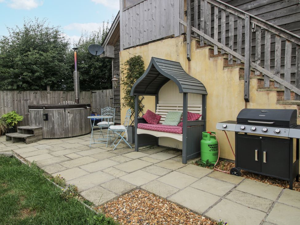 A garden with a hot tub, seating area, and barbecue at Stable Cottage in Norbury near Bishop's Castle
