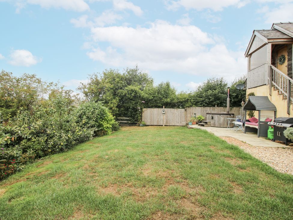 A garden area with grass and a seating arrangement at Stable Cottage in Norbury near Bishop's Castle
