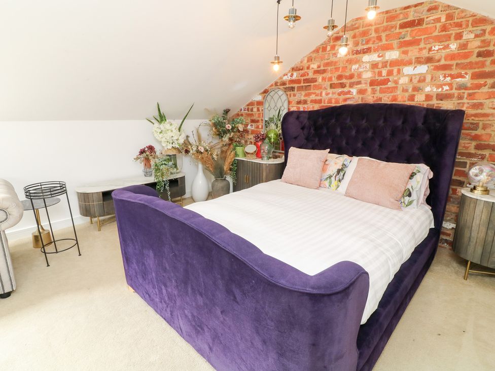 A bedroom with a purple bed and flower arrangements at Hideaway in Scampton