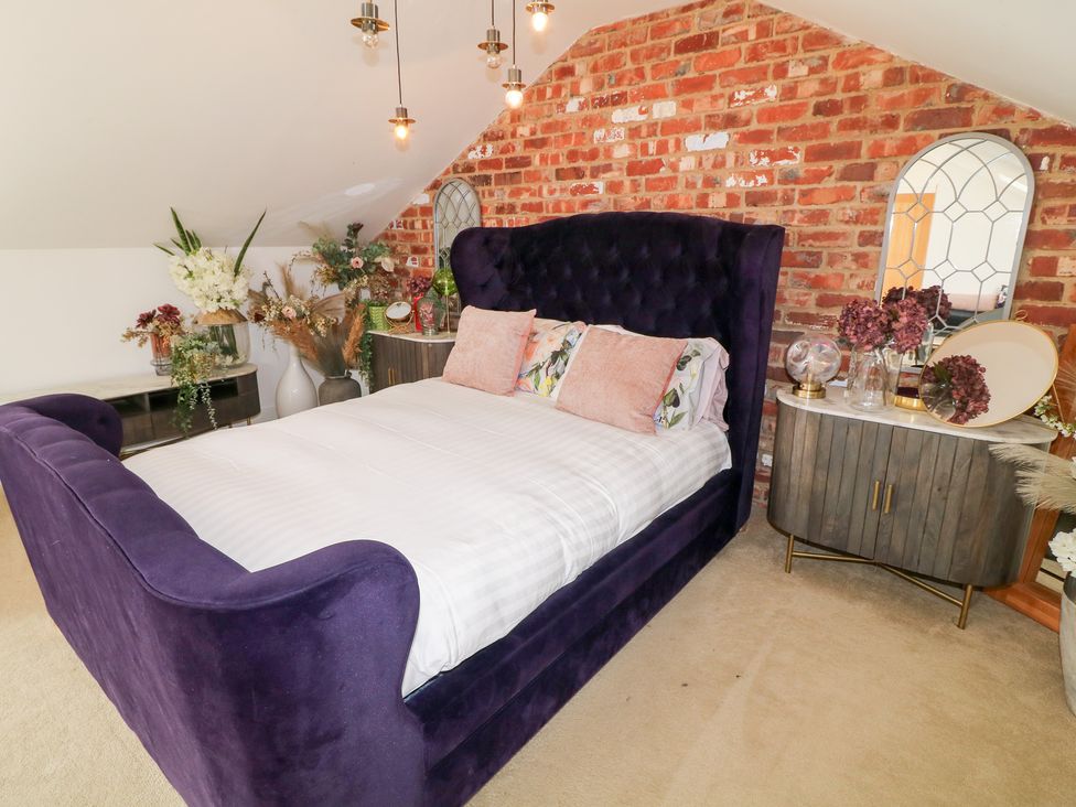 A bedroom with a purple bed and decorative flowers at Hideaway in Scampton