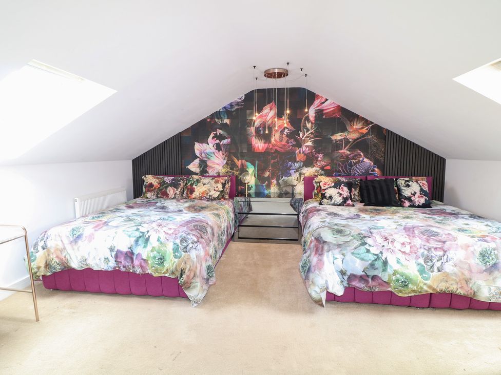 A bedroom with two beds and a floral wall design at Hideaway in Scampton