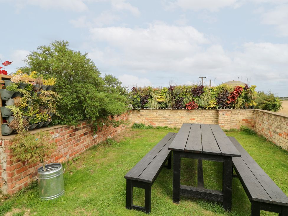 A garden with a table and benches at Hideaway in Scampton