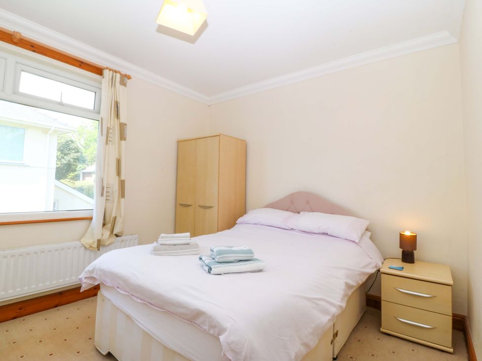 A bedroom with a bed and wardrobe at Cwm Eilir in Criccieth