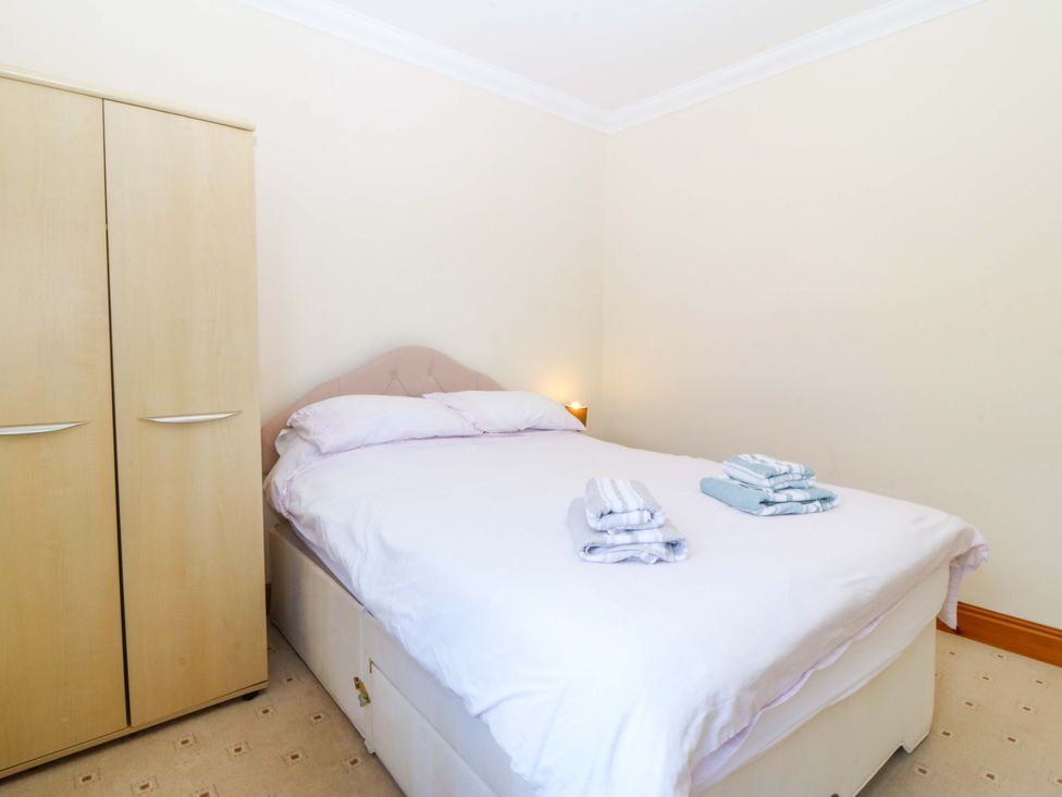 A bedroom with a bed and wardrobe at Cwm Eilir in Criccieth