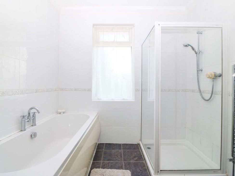 A bathroom with a bathtub and shower at Cwm Eilir in Criccieth