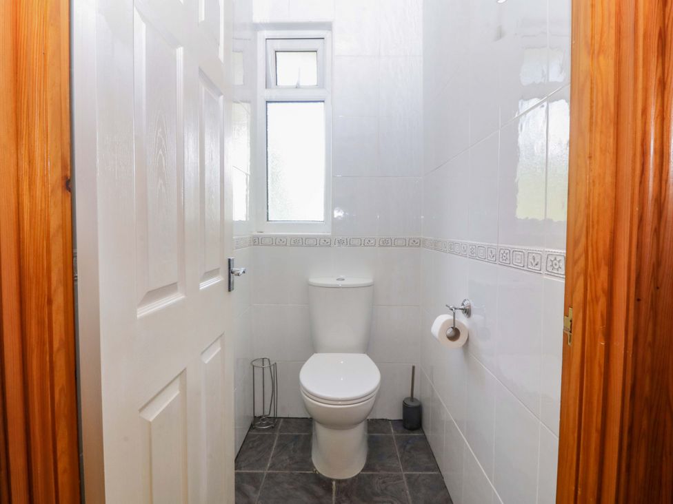 A bathroom with a toilet and window at Cwm Eilir Criccieth