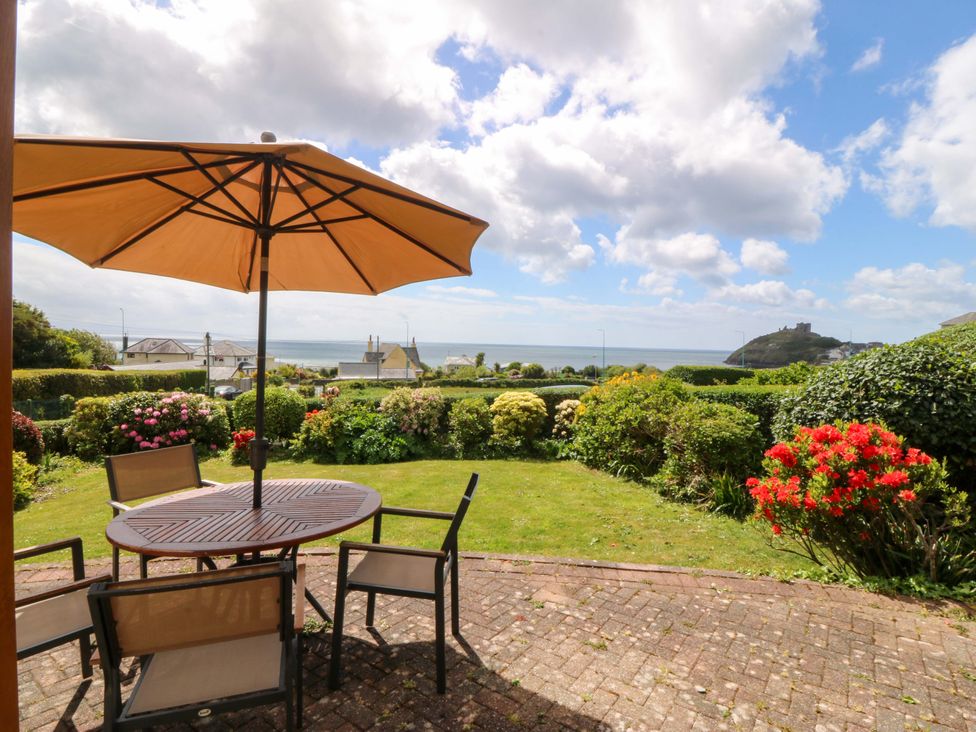 A garden with a table and chairs under an umbrella at Cwm Eilir in Criccieth
