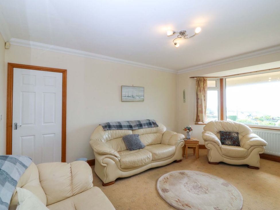 A living room with sofas and a door at Cwm Eilir Criccieth