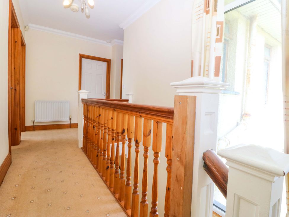 A hallway with balustrade and door at Cwm Eilir in Criccieth