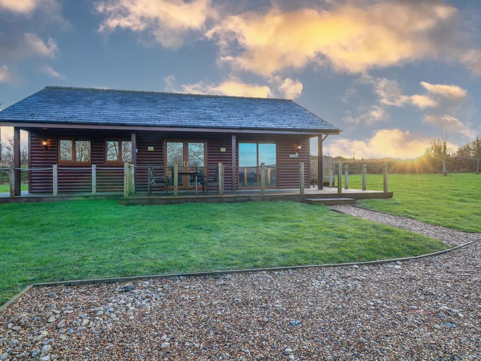 A cabin with a deck and a gravel pathway at Lodge 2 South Hykeham