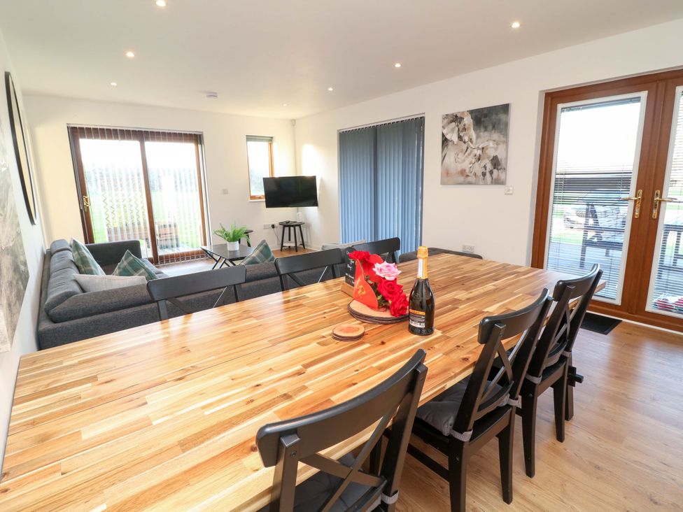 A dining room with a table and sofa at Lodge 2 in South Hykeham