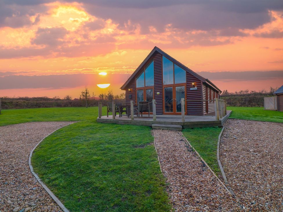 A cabin with a deck and chairs during sunset at Lodge 3 Thorpe-On-The-Hill