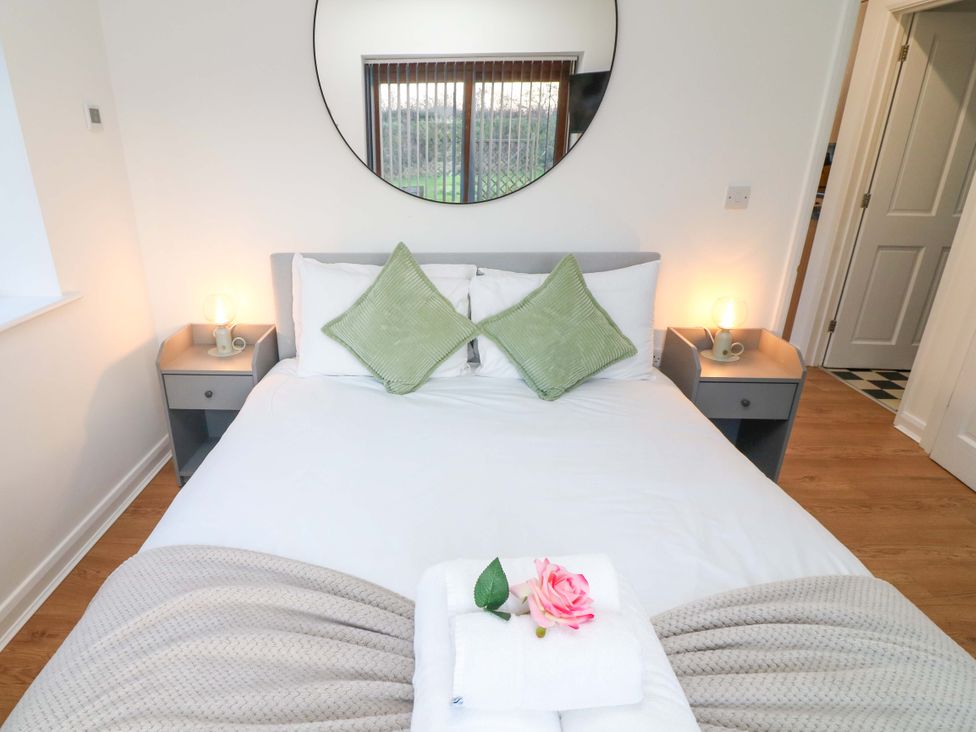 A bedroom with a bed and mirror at Lodge 3 in Thorpe-On-The-Hill