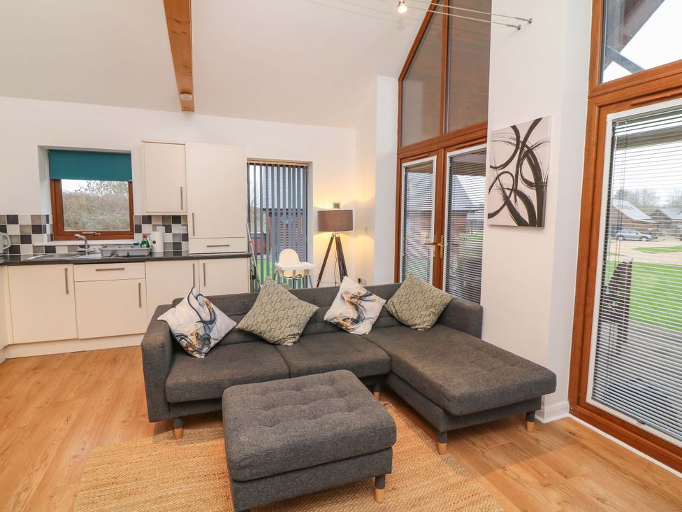 A living room with a sofa and kitchen in Lodge 4 South Hykeham