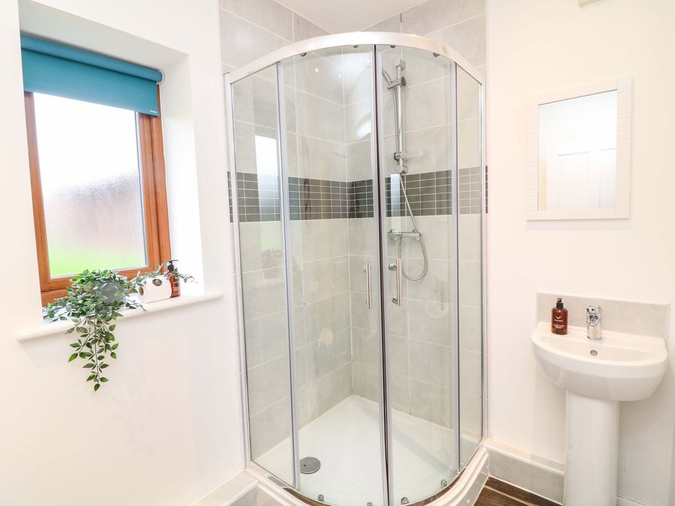 A bathroom with a shower, sink, and window at Lodge 7 in South Hykeham