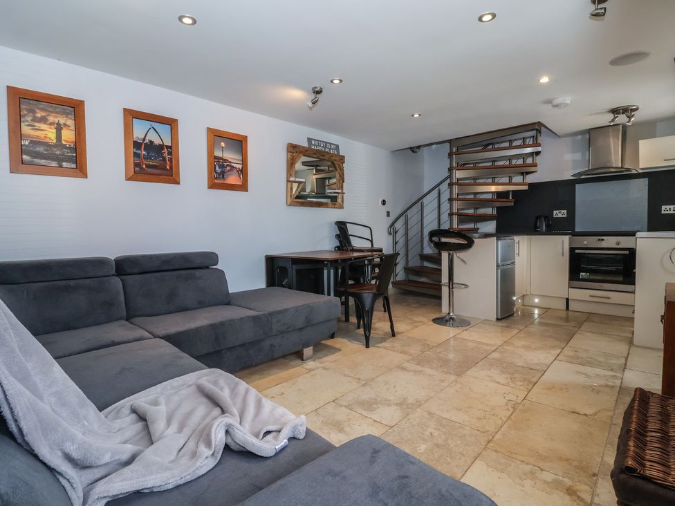 A living room with a sofa and kitchenette at 5 Hall Yard in Whitby