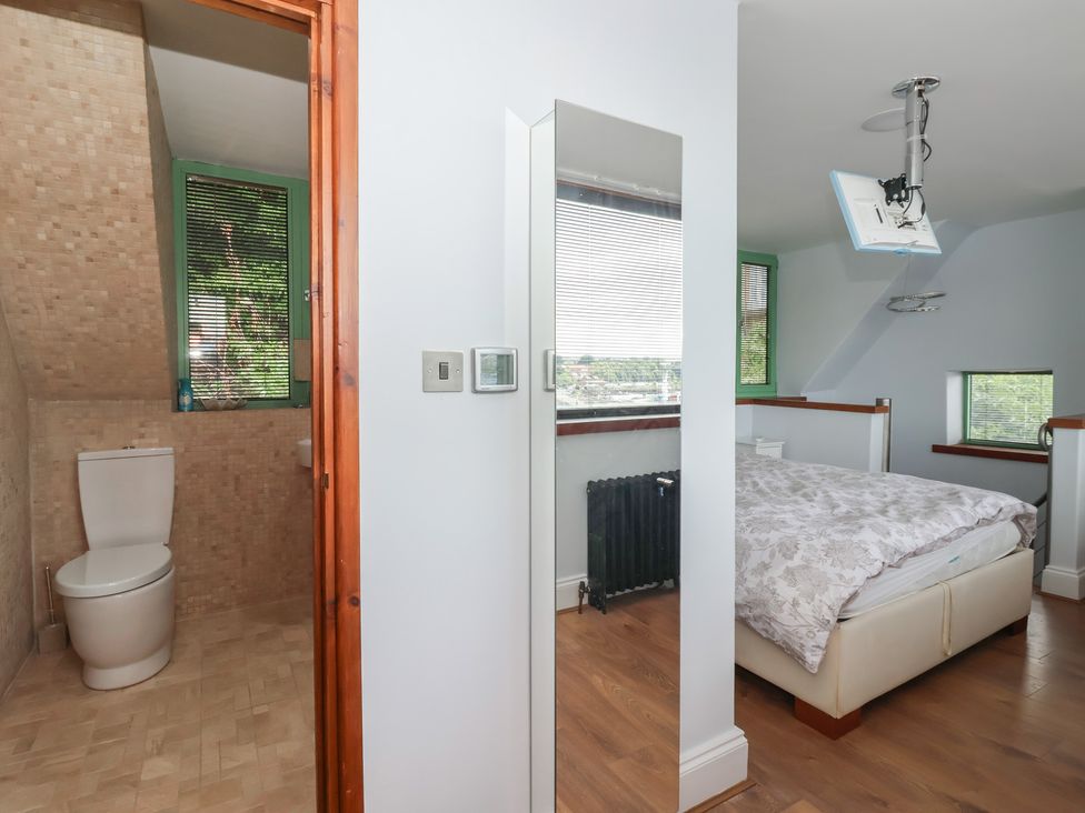 A bathroom with a toilet and a bedroom with a bed at 5 Hall Yard in Whitby