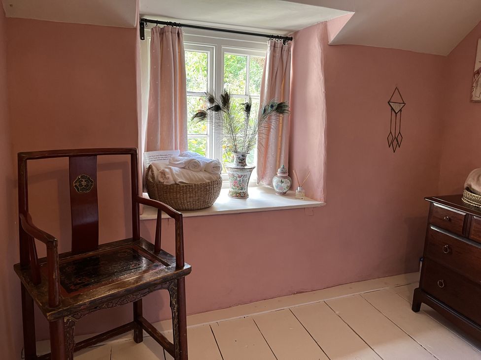 A bedroom with a chair and window displaying towels and a vase at 4 Cumberland Cottages Ringmore near Challaborough