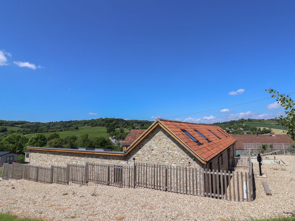 An outdoor view of a house with a gravel area and fence at The Stables in Uplyme