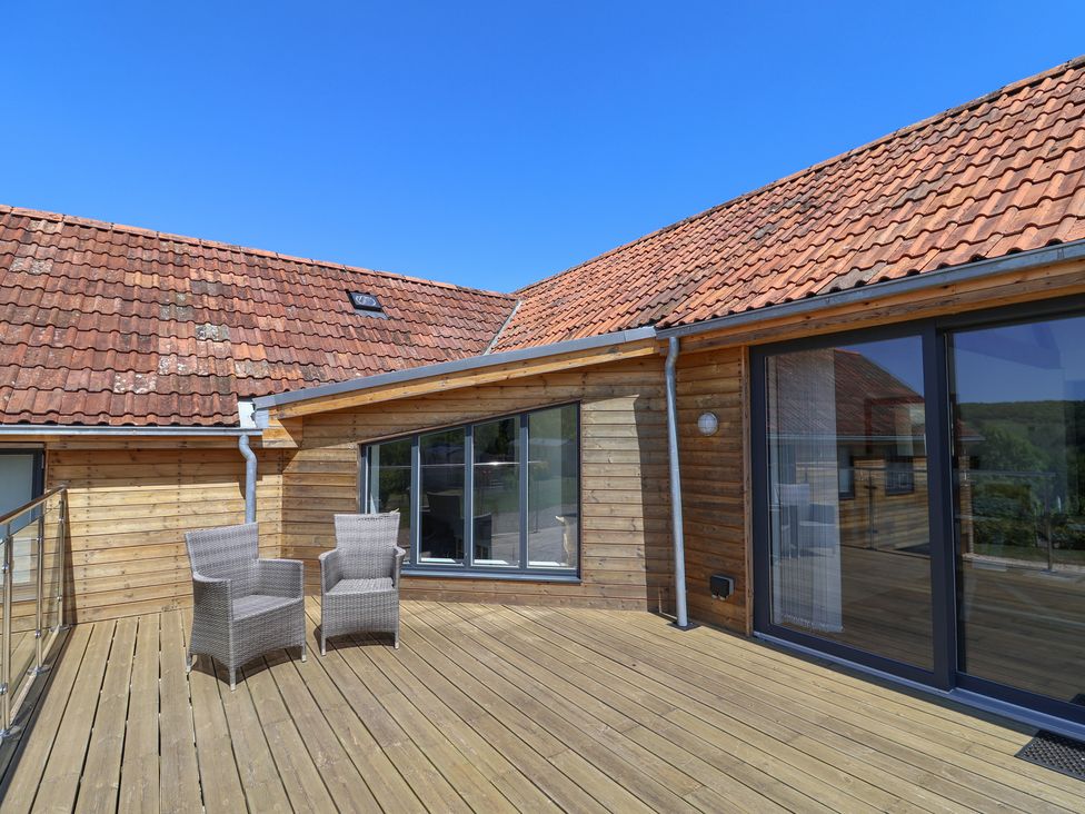 An outdoor area with two chairs and wooden decking at The Stables in Uplyme