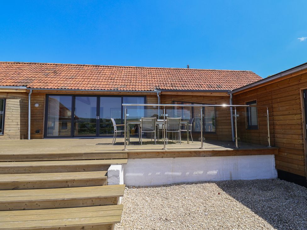 An outdoor dining area with a wooden deck at The Stables in Uplyme