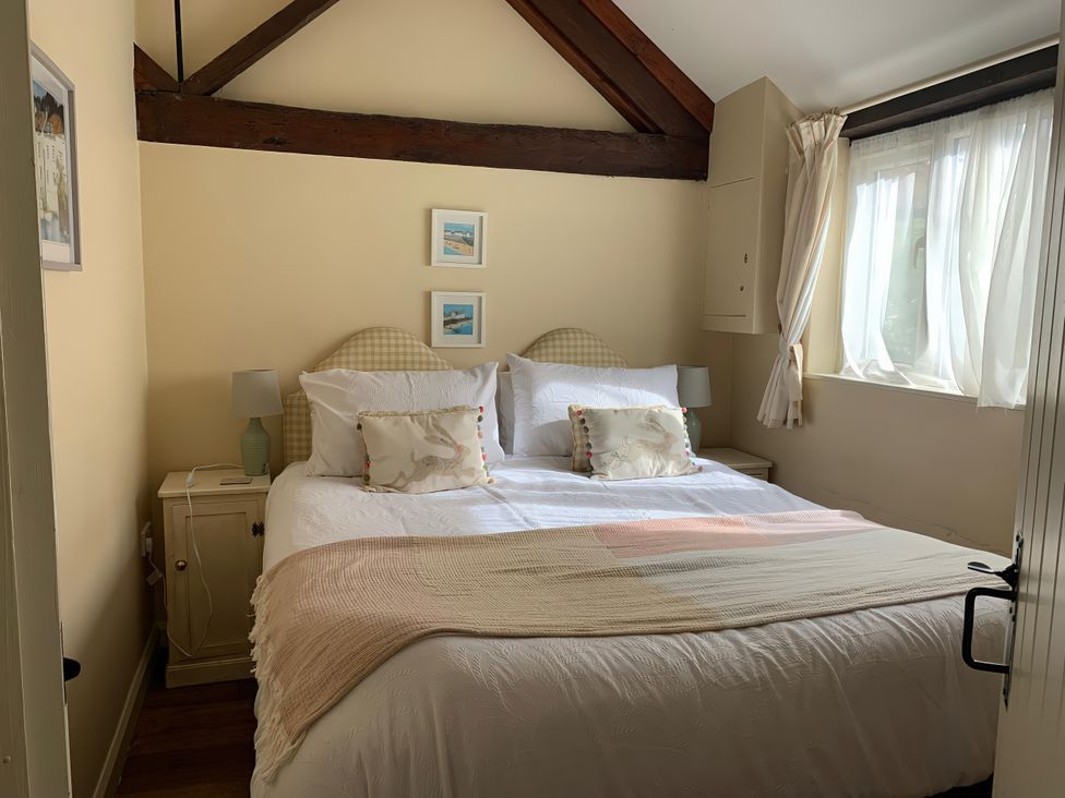 A bedroom with a bed, lamp, nightstand and pictures at The Calf Pen in Colyton