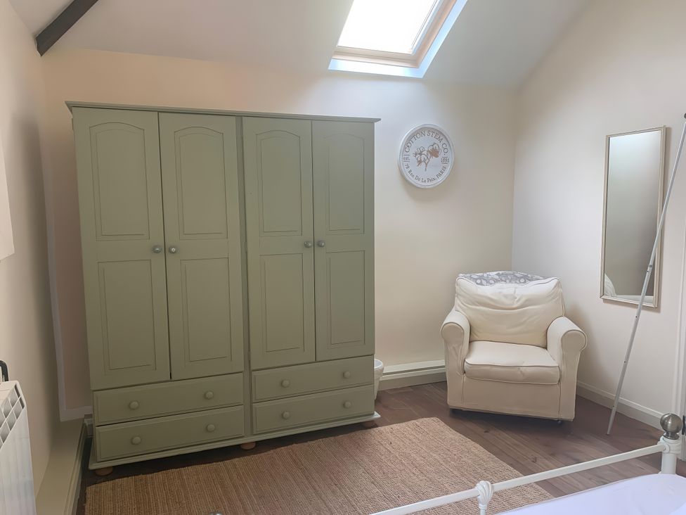 A bedroom with a wardrobe and an armchair at The Calf Pen in Colyton